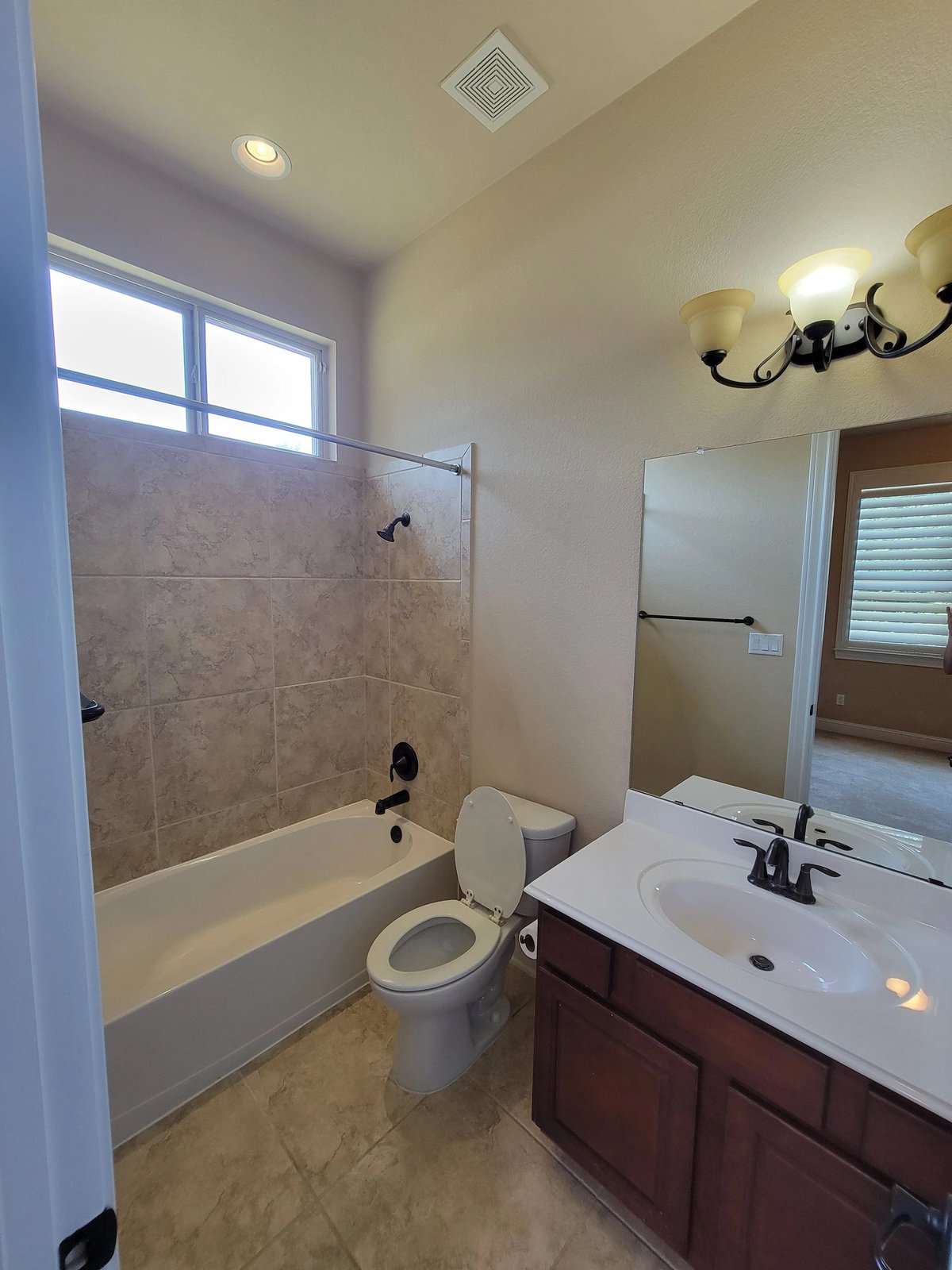 Modern bathroom with white vanity sink, dark wood cabinet, toilet, and glass-enclosed shower with tile surround