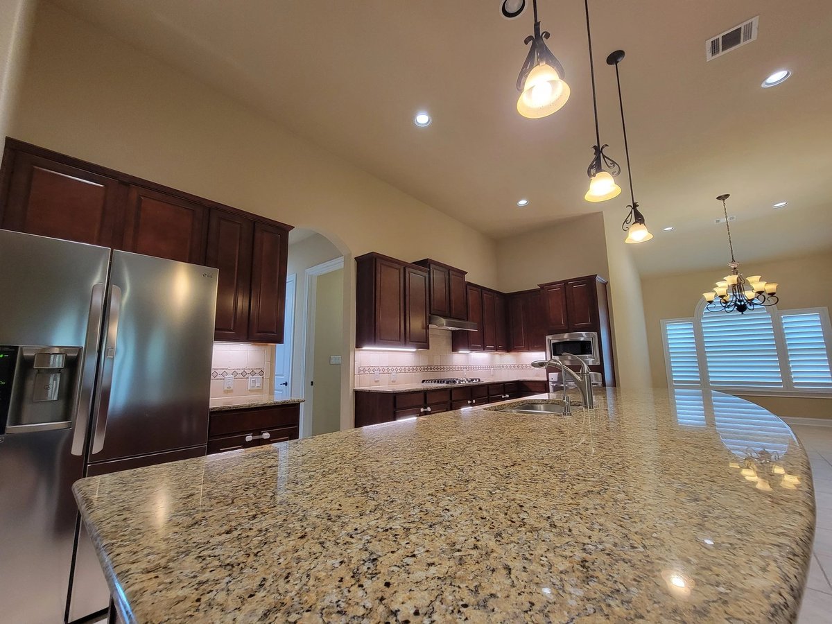 Gourmet kitchen detail at 16213 Maritime Alps Way — granite island, dark wood cabinets, stainless steel appliances, pendant lighting. Falconhead West Austin TX 78738 4BR 4BA. Real Estates Of Texas listing by Gayle Sparkman. MLS 8675253