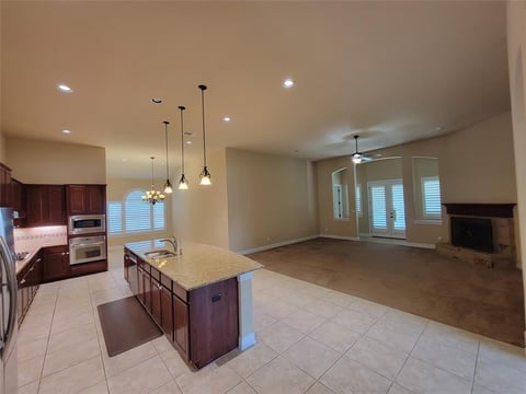 Open concept kitchen and living room with island, pendant lights, and hardwood flooring in dining area